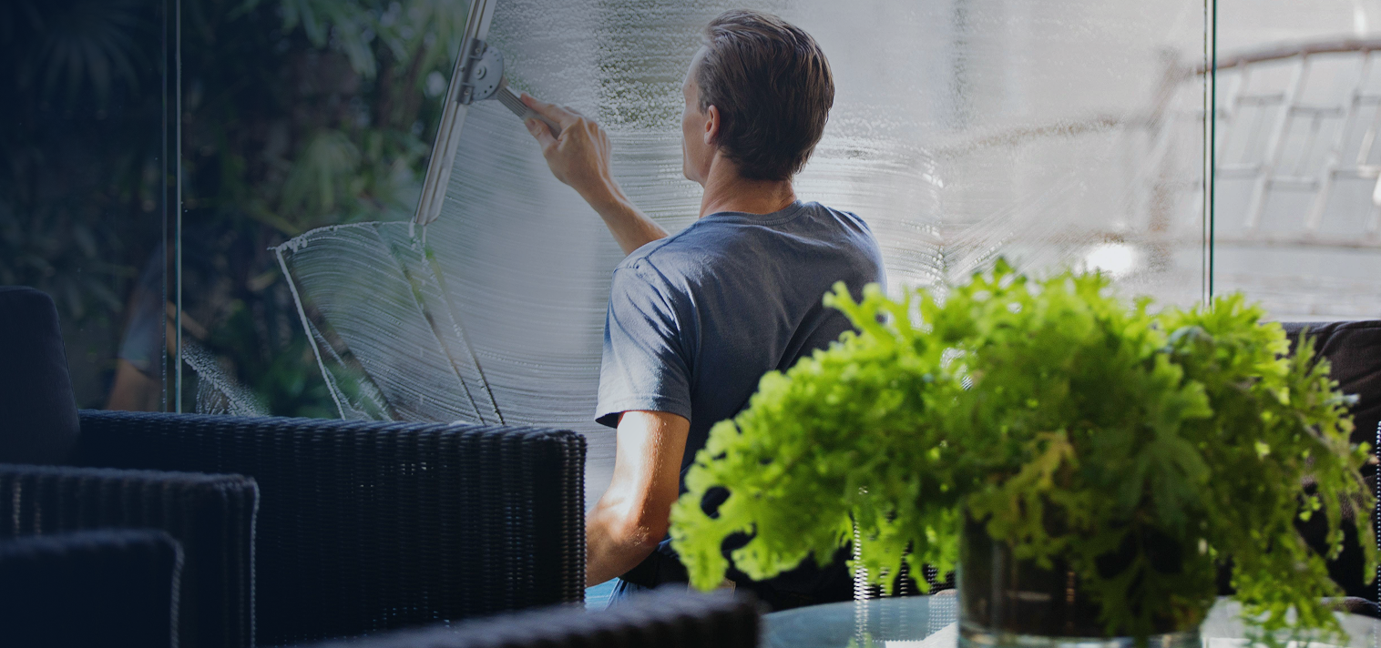Person painting a large canvas in a room with plants and furniture.