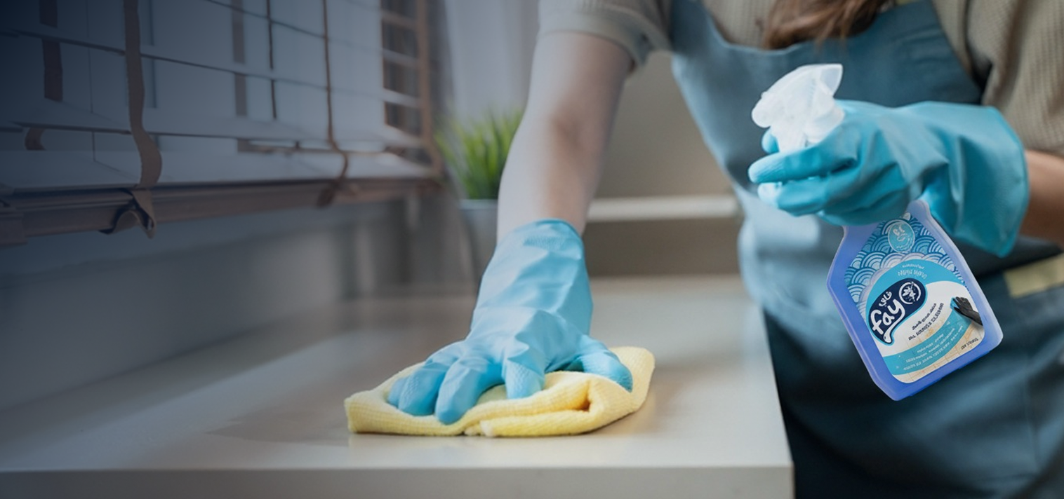 Person cleaning a surface with a yellow cloth and a bottle of Clorox wipes.